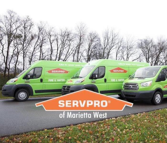three green SERVPRO trucks lined up on a side street